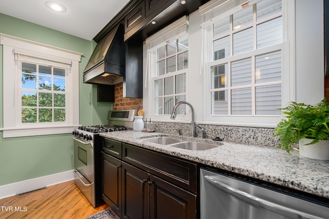 kitchen featuring visible vents, light wood-style flooring, custom range hood, appliances with stainless steel finishes, and a sink