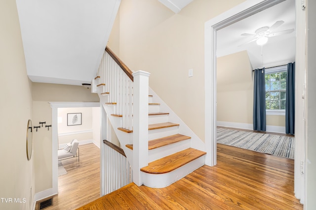 stairs featuring a ceiling fan, visible vents, baseboards, and wood finished floors