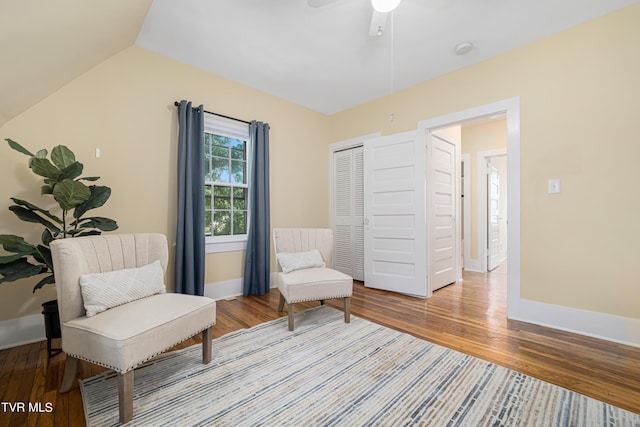 living area featuring vaulted ceiling, baseboards, and wood finished floors