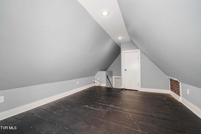 additional living space featuring dark wood-style floors, recessed lighting, visible vents, vaulted ceiling, and baseboards