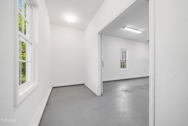 spare room featuring finished concrete floors and baseboards