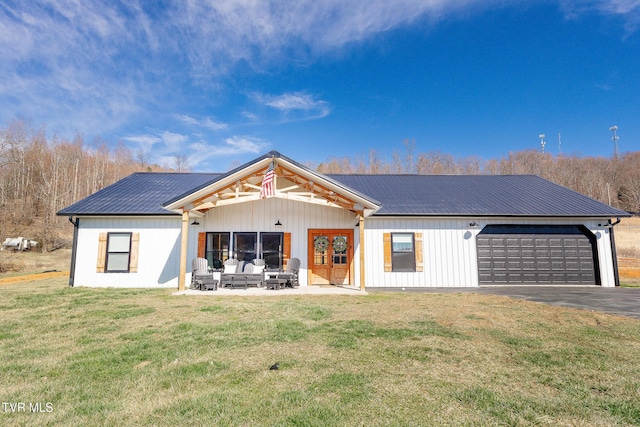 view of front of home with metal roof, a patio, an attached garage, a front lawn, and board and batten siding