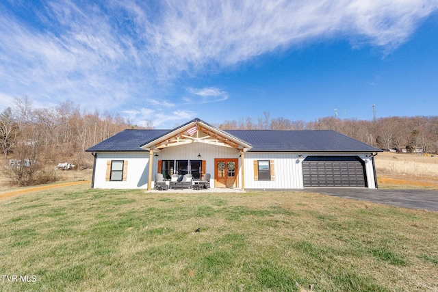 modern farmhouse with an attached garage, metal roof, and a front yard