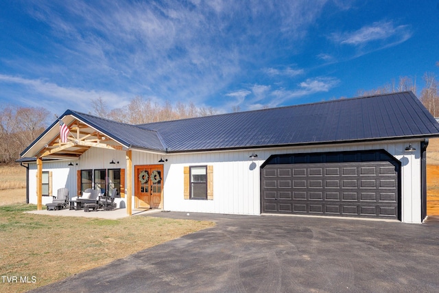 modern inspired farmhouse with a garage, a patio area, a front lawn, and metal roof