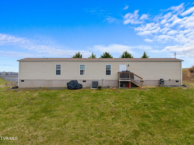 back of property with crawl space, cooling unit, and a lawn