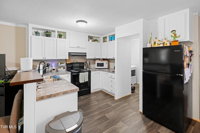 kitchen featuring under cabinet range hood, a peninsula, a sink, black appliances, and dark wood finished floors