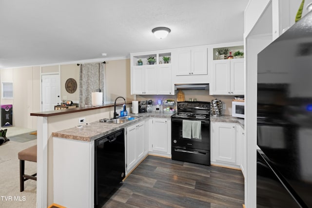 kitchen featuring white cabinets, a sink, a peninsula, under cabinet range hood, and black appliances