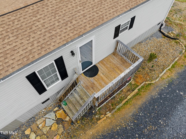 view of exterior entry featuring roof with shingles