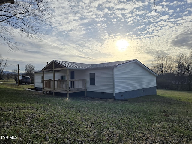 view of property exterior with crawl space, a wooden deck, metal roof, and a yard