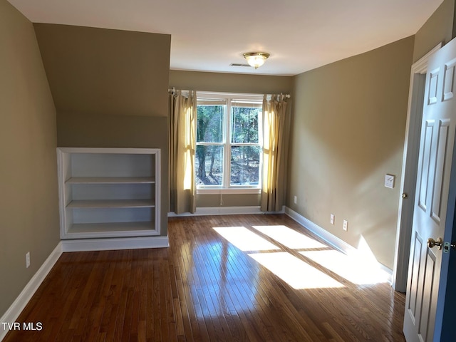 spare room with built in features, baseboards, and hardwood / wood-style flooring