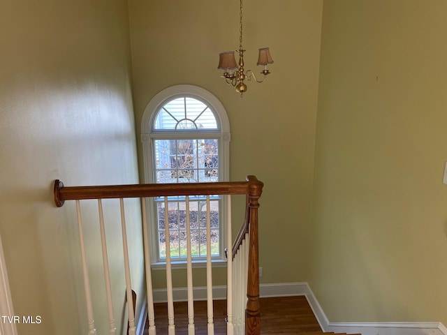 stairway with baseboards, a chandelier, and wood finished floors