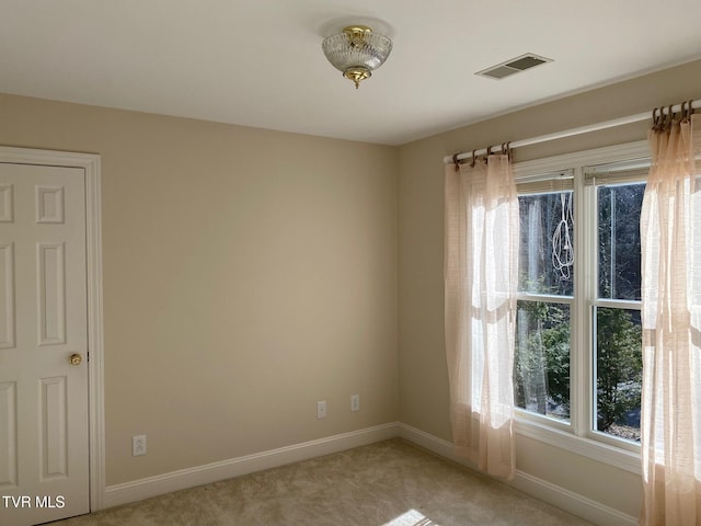 spare room with light carpet, baseboards, and visible vents