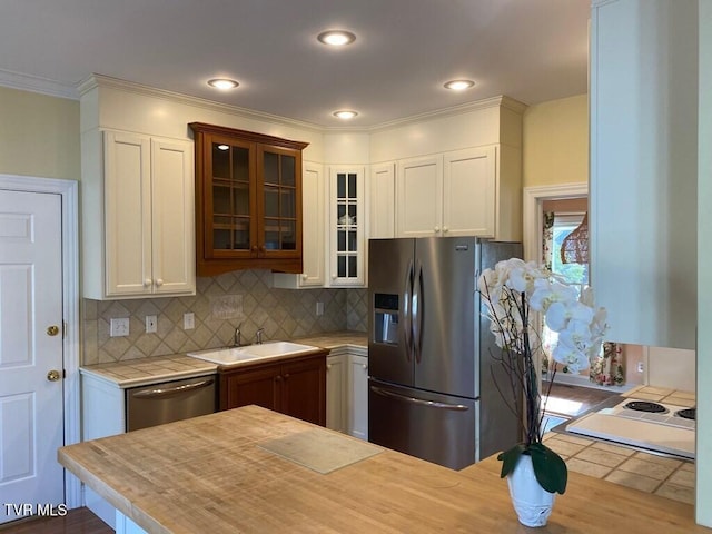 kitchen featuring white cabinets, glass insert cabinets, a sink, stainless steel appliances, and backsplash