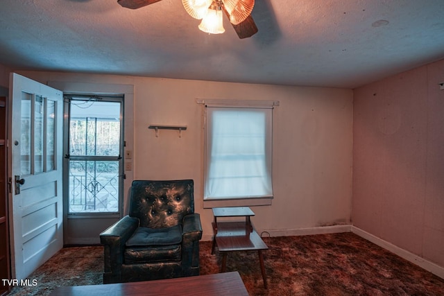 sitting room featuring carpet, baseboards, ceiling fan, and a textured ceiling