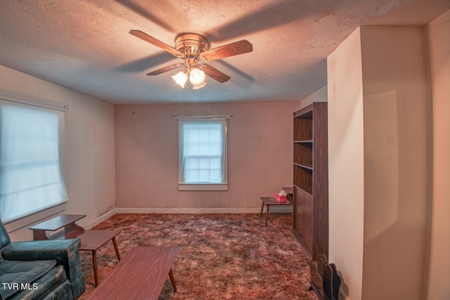 interior space with a ceiling fan, carpet flooring, a textured ceiling, and baseboards