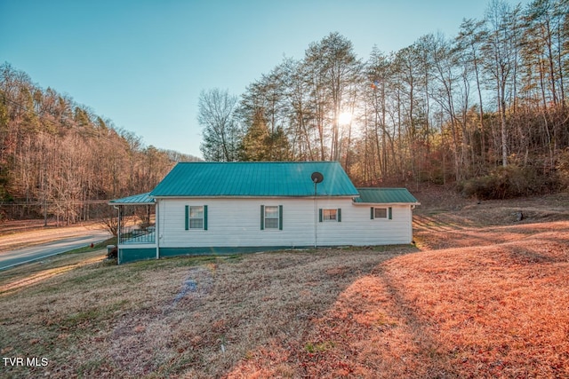 back of property with metal roof and a lawn