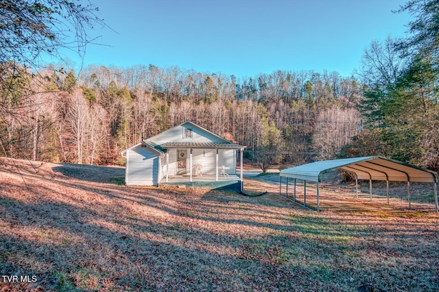 view of outbuilding featuring a forest view, a carport, and an outdoor structure