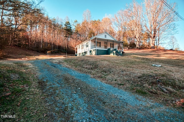 view of front of house featuring a porch, a front lawn, and gravel driveway