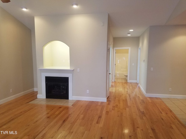 unfurnished living room with light wood-type flooring, a fireplace with flush hearth, baseboards, and recessed lighting