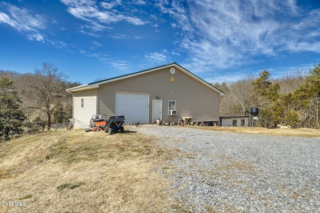 view of side of property featuring a garage, an outdoor structure, and gravel driveway