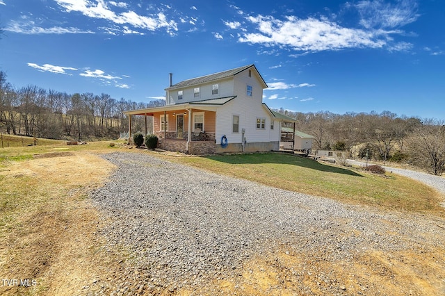 view of front of home with driveway, covered porch, and a front yard