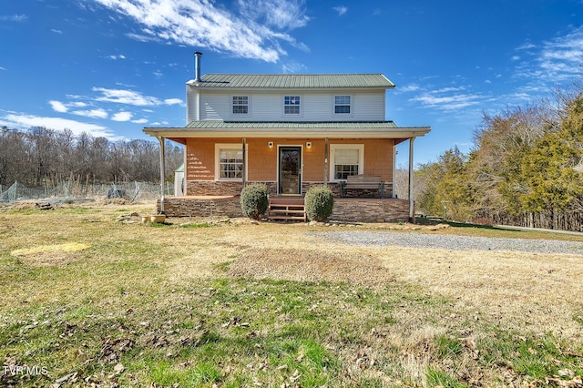 farmhouse featuring a porch, stone siding, metal roof, and a front lawn