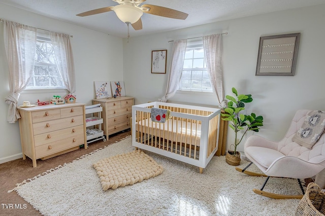 bedroom featuring a nursery area, a ceiling fan, and baseboards