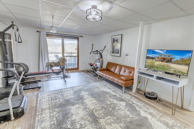 workout room with a paneled ceiling, baseboards, and wood finished floors