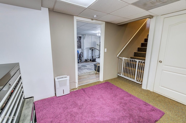 interior space featuring a paneled ceiling, carpet flooring, and stairway