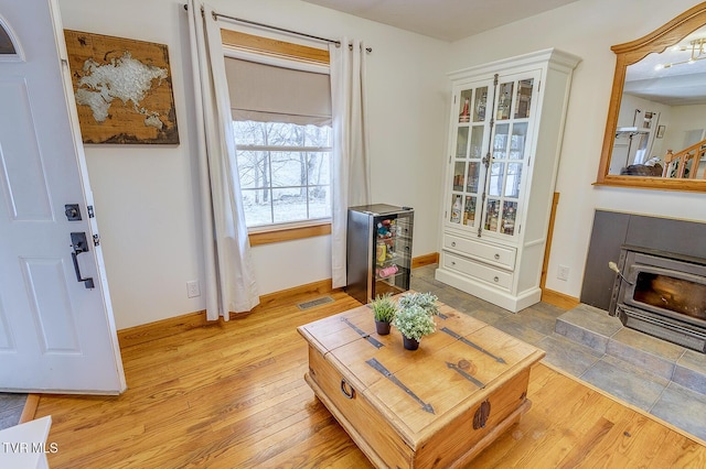 sitting room featuring light wood finished floors, a fireplace, visible vents, and baseboards