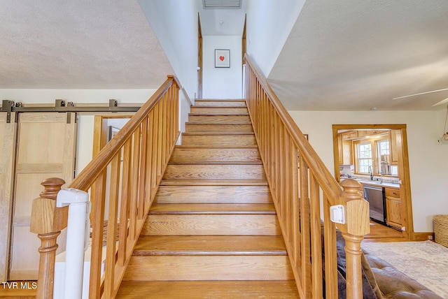 stairs featuring a textured ceiling, a barn door, and hardwood / wood-style flooring