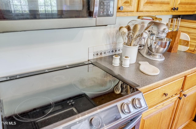 interior details featuring electric range oven, stainless steel microwave, and dark countertops