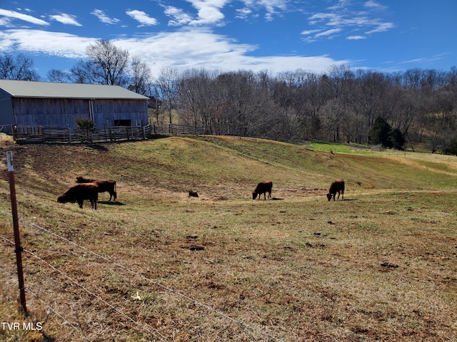 view of yard featuring a pole building, a rural view, an outdoor structure, and fence