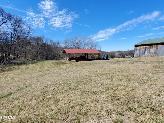 view of yard featuring a pole building, a rural view, and an outdoor structure