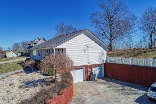 view of side of home featuring a garage, driveway, and fence