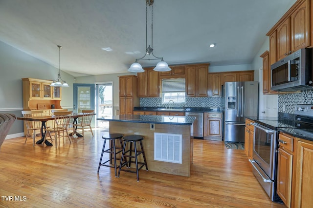 kitchen featuring lofted ceiling, visible vents, appliances with stainless steel finishes, and brown cabinets