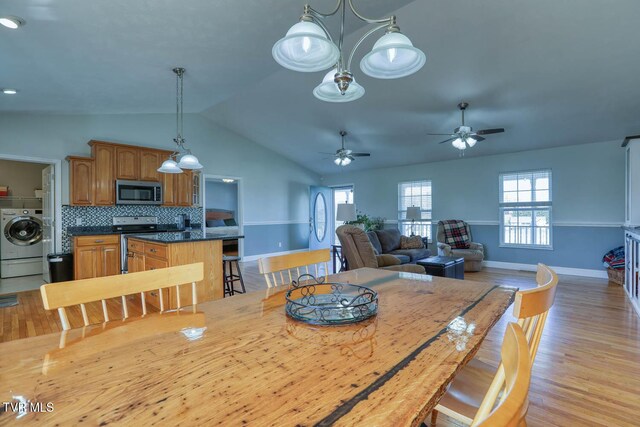 dining room featuring washer / clothes dryer, light wood-style flooring, a ceiling fan, vaulted ceiling, and baseboards