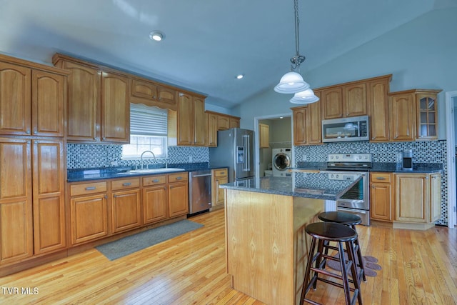 kitchen with vaulted ceiling, appliances with stainless steel finishes, brown cabinetry, and a sink