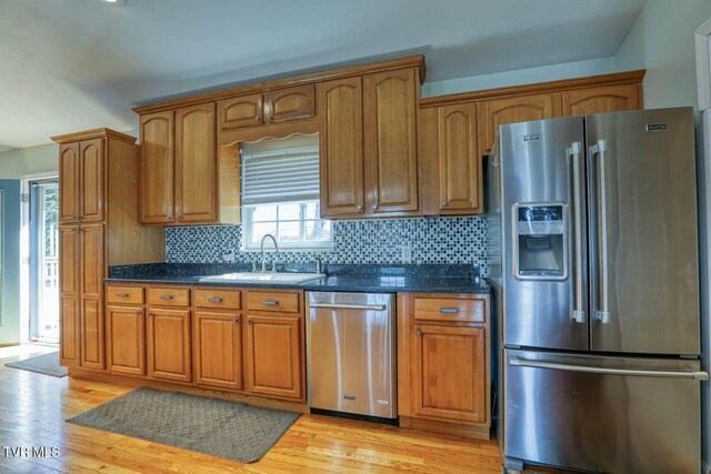 kitchen featuring brown cabinetry, light wood-style floors, stainless steel appliances, and a sink