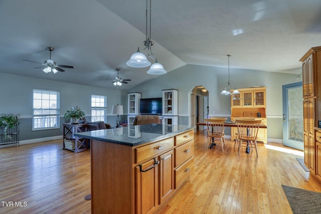 kitchen featuring lofted ceiling, a center island, decorative light fixtures, and light wood-style flooring