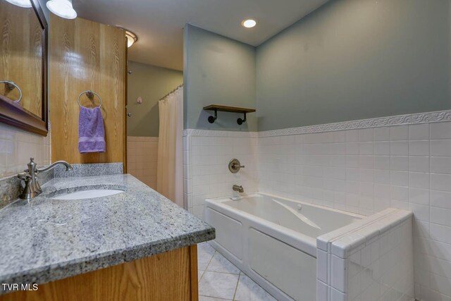 full bath with a wainscoted wall, a garden tub, tile walls, vanity, and tile patterned flooring