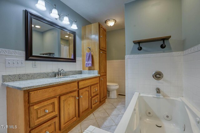 bathroom featuring a wainscoted wall, tile walls, vanity, a whirlpool tub, and tile patterned floors