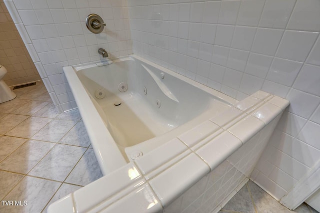 bathroom with visible vents, a tub with jets, tile walls, and tile patterned floors