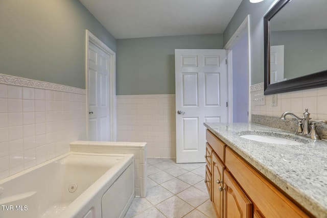 bathroom with a wainscoted wall, a jetted tub, tile patterned flooring, vanity, and tile walls