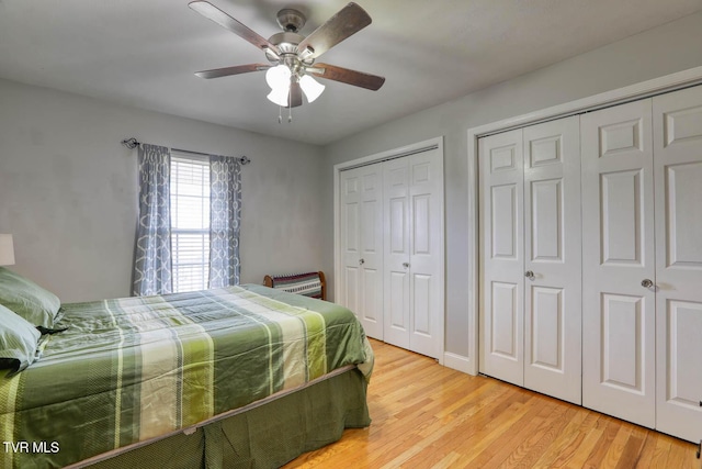 bedroom featuring ceiling fan, light wood-style flooring, and multiple closets