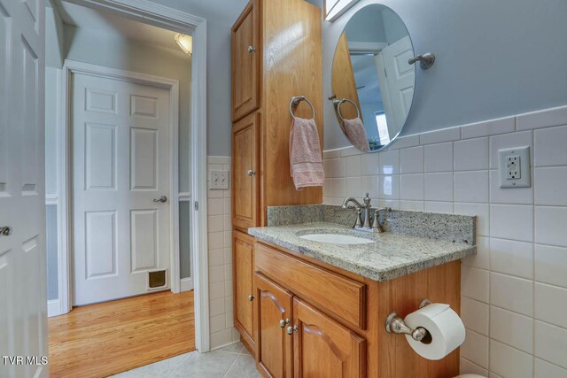 half bathroom featuring tile patterned flooring, vanity, and tile walls