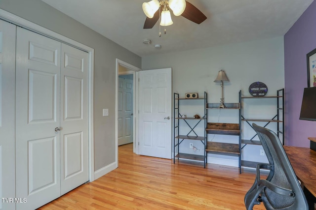 office area with baseboards, a ceiling fan, and light wood-style floors