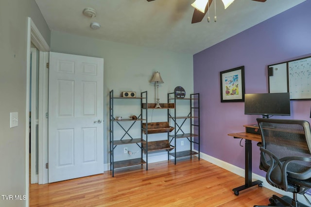 office area with baseboards, a ceiling fan, and light wood-style floors