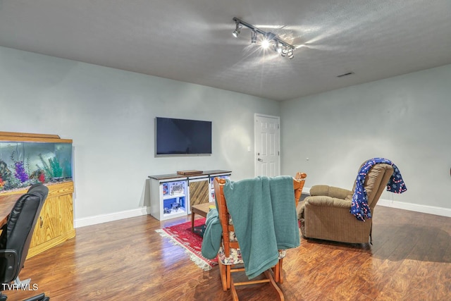 living area with visible vents, baseboards, and wood finished floors