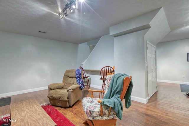 sitting room with wood finished floors, visible vents, and baseboards